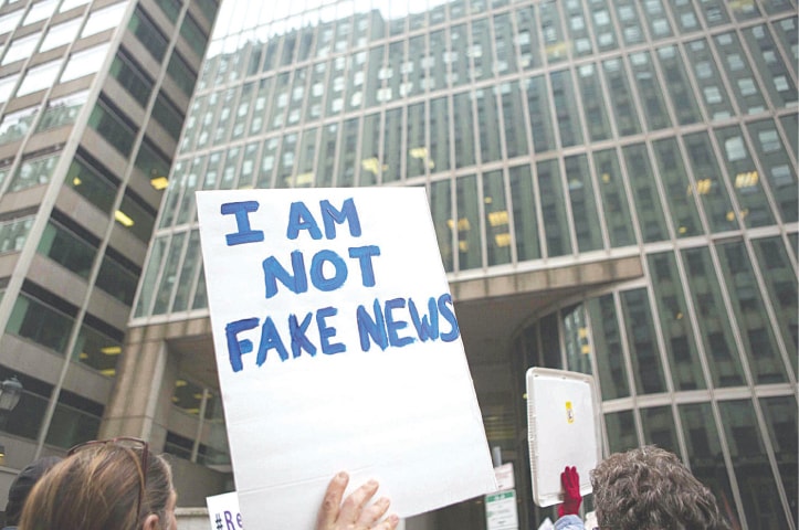 A protester holds an ‘I am not fake news’ sign | AFP