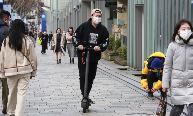 A man wearing a face mask to protect against the spread of the coronavirus rides a scooter along a sidewalk in Tokyo on February 2, 2021. — AP