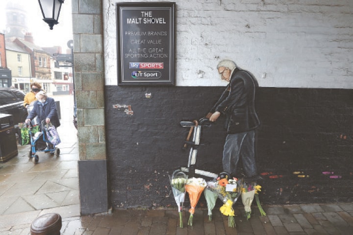 CAPTAIN Tom Moore’s admirers walk beside his mural in Yorkshire.—Reuters