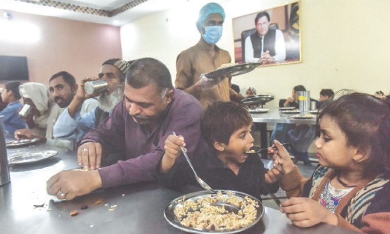 A FAMILY — a father [left] and his two children — is among many who are offered meals at Surjani Town Panahgah everyday.—Fahim Siddiqi / White  Star