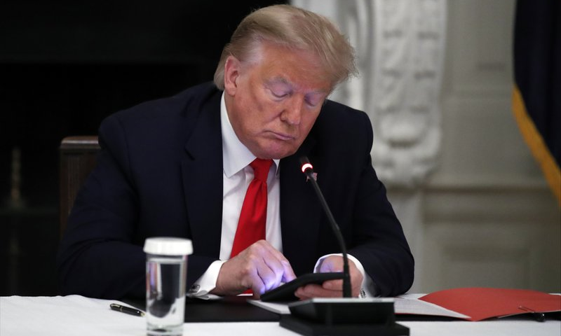 President Donald Trump looks at his phone during a roundtable with governors on the reopening of America's small businesses, in the State Dining Room of the White House in Washington. &mdash; AP/File