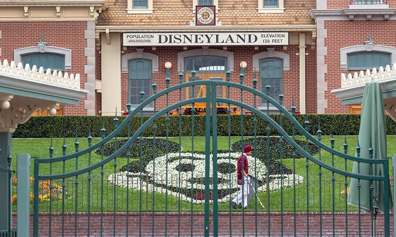 In this file photo taken on March 14, 2020 an employee cleans the grounds behind the closed gates of Disneyland Park on the first day of the closure of Disneyland and Disney California Adventure theme parks as fear of the spread of coronavirus continue, in Anaheim, California. — AFP