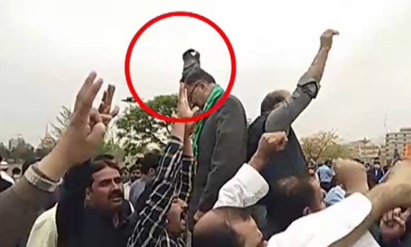 Screenshot from a video clip shoes a shoe flying at PML-N leader Ahsan Iqbal. — DawnNewsTV