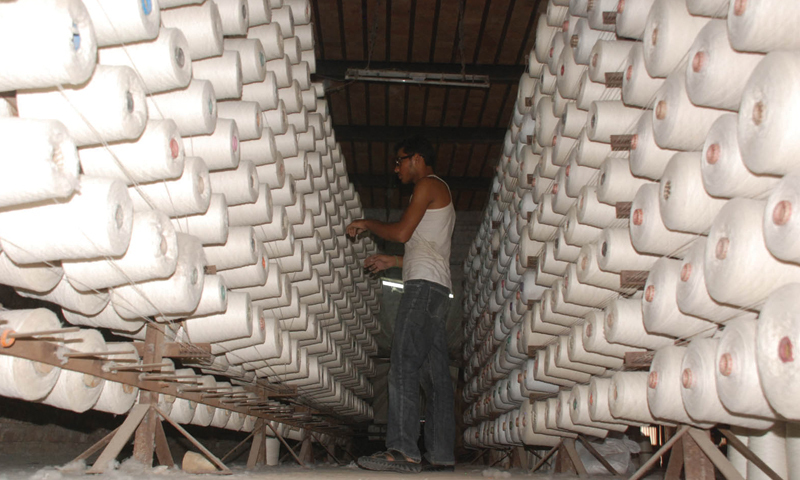 FAISALABAD: An employee works on spindles in a yarn factory. —INP/File