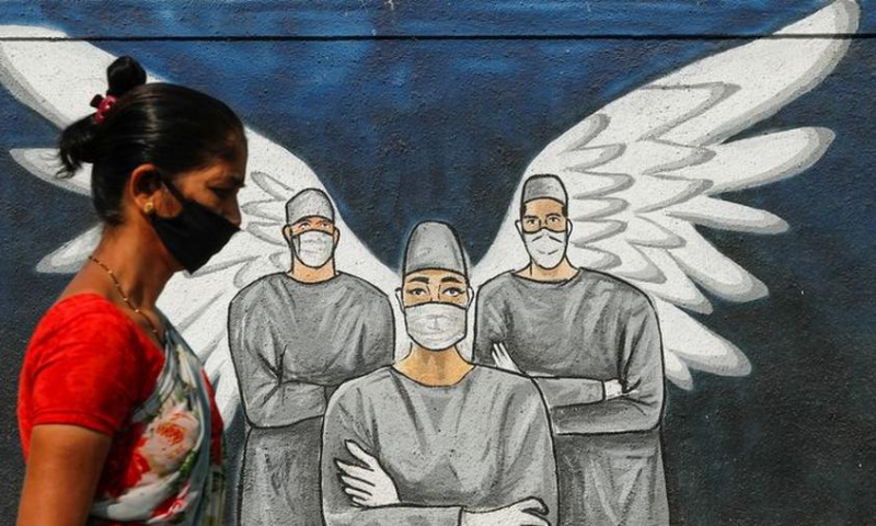 A woman wearing a protective mask walks past graffiti amidst the spread of the coronavirus, on a street in Navi Mumbai. — Reuters
