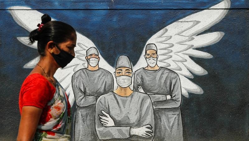 A woman wearing a protective face mask walks past graffiti in Mumbai on March 8. — Reuters