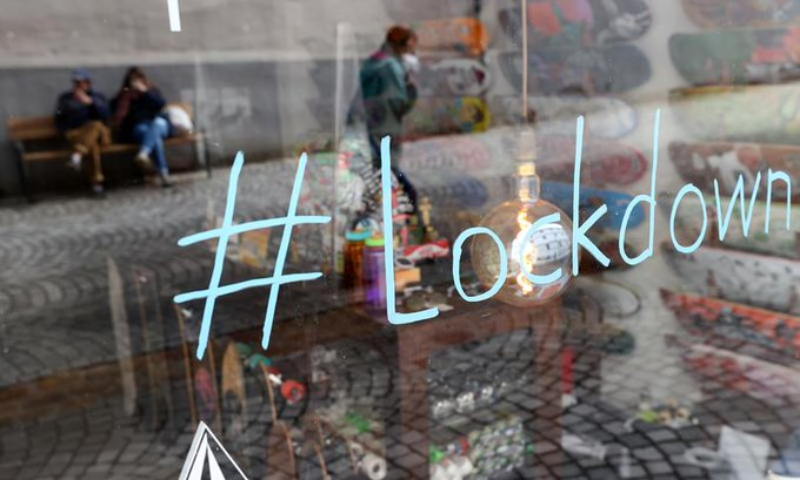 People are reflected in a shop window as they enjoy some sun, as the spread of the coronavirus disease continues in Tuebingen, Germany. — Reuters