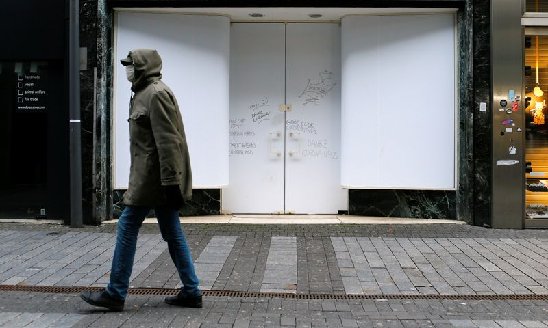 A man walks along a closed shop at the main shopping street Hohe Strasse amid the coronavirus pandemic in Cologne, Germany, March 18. &mdash; Reuters