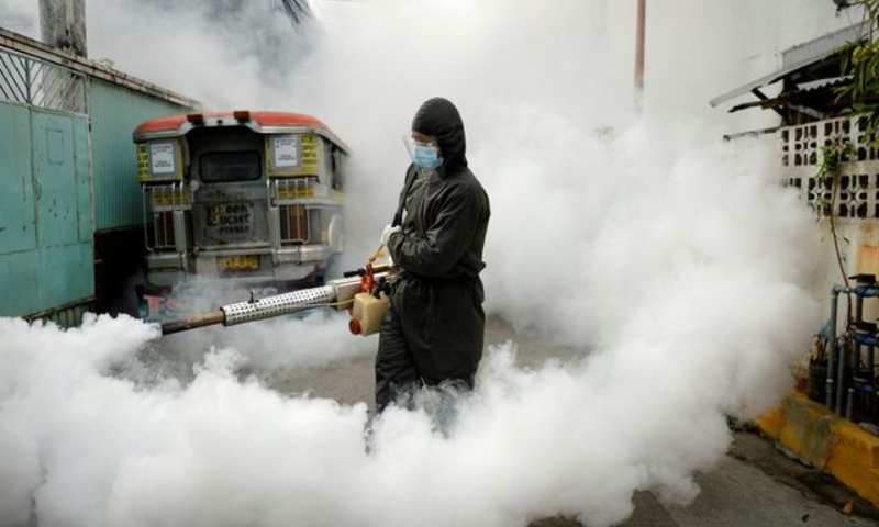 A worker in a hazmat suit disinfects a street as a preventive measure against the coronavirus at a village in Manila, March 19. — Reuters
