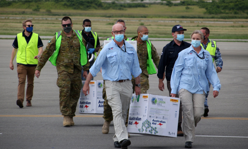 Australian officials carry boxes containing some 8,000 initial doses of the AstraZeneca vaccine following their arrival on board a Royal Australian Air Force plane at the Port Moresby international airport. — AFP