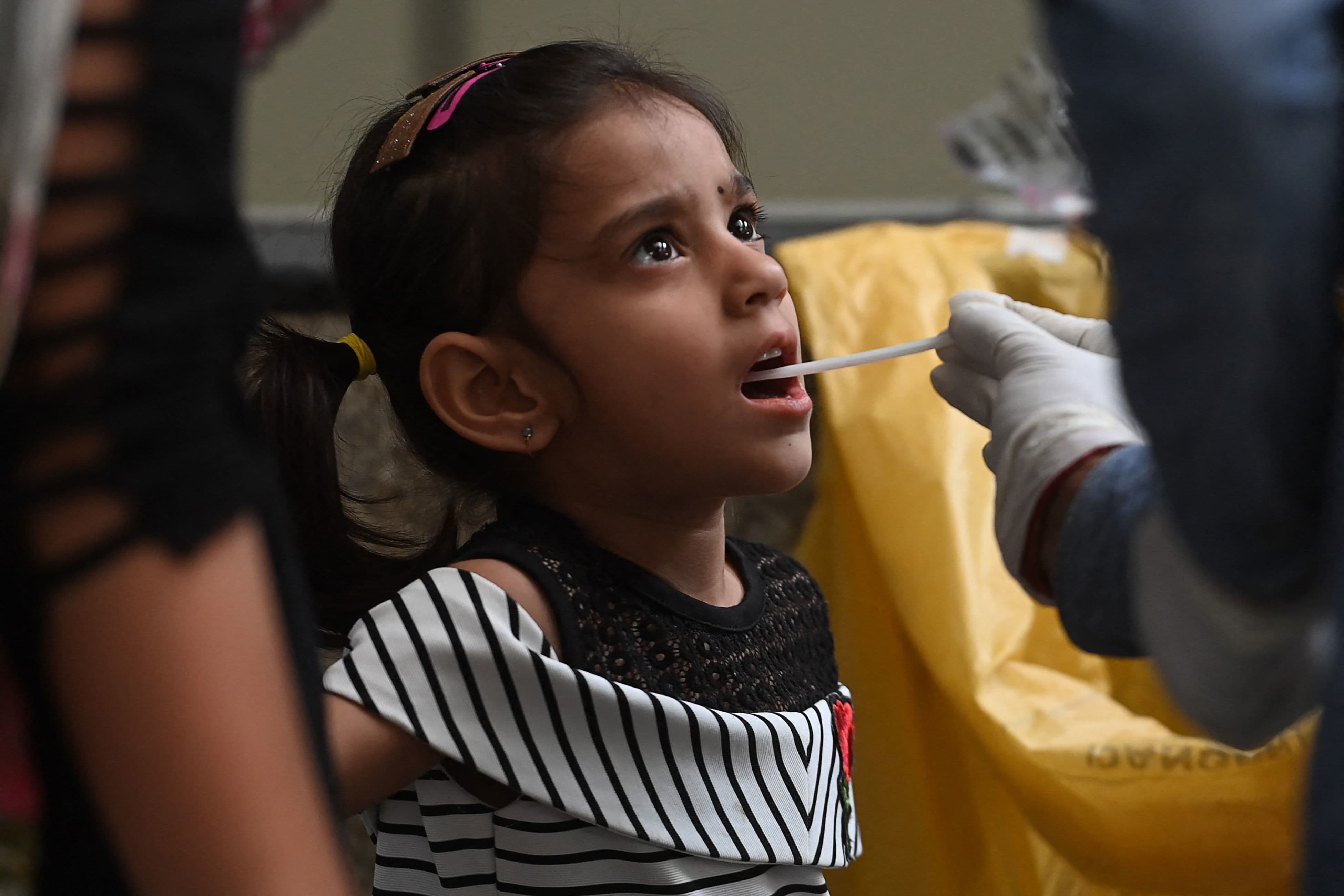 A health worker collects a swab sample from a child in New Delhi on March 24. &mdash; AFP