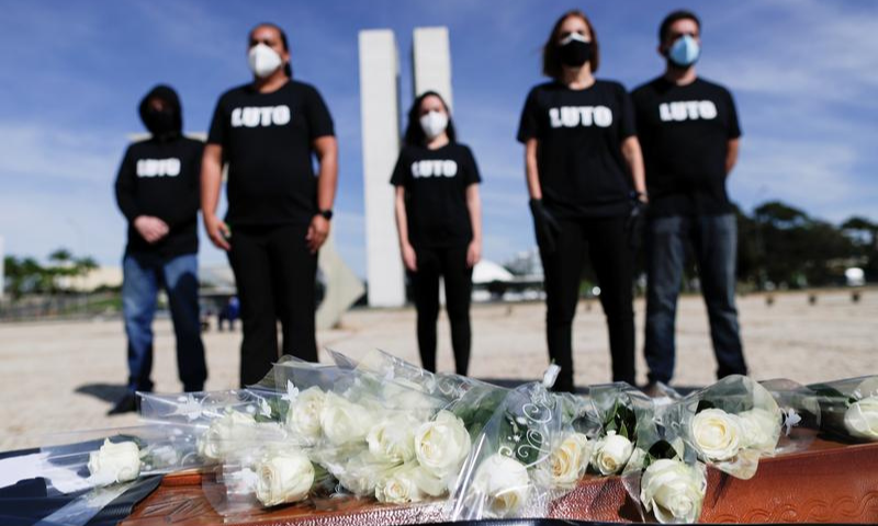 Health care workers stand behind a coffin that represents dead colleagues during a protest against Brazil's President Jair Bolsonaro and his handling of the coronavirus crisis. — Reuters