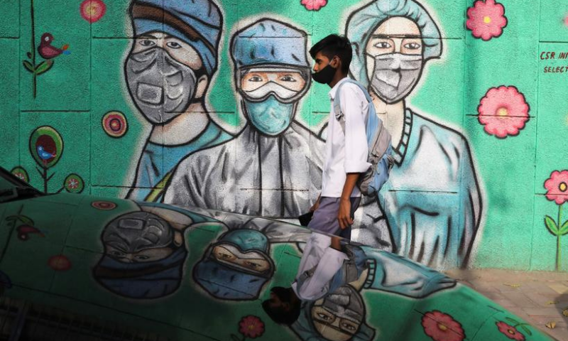 A boy walks past graffiti amidst the spread of the coronavirus on a street in New Delhi, India. — Reuters