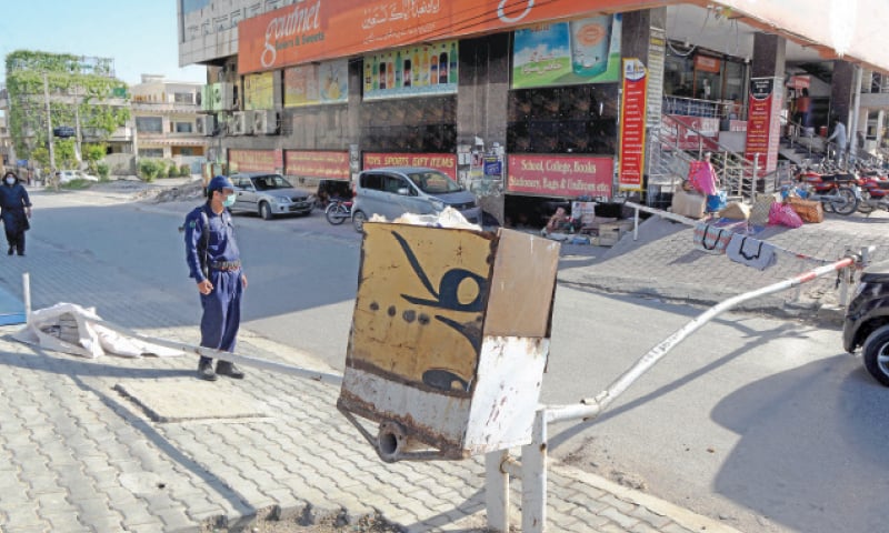 A guard stands near a barrier in PWD Colony Block C which was sealed on Monday after emergence of Covid-19 cases. — Photo by Mohammad Asim