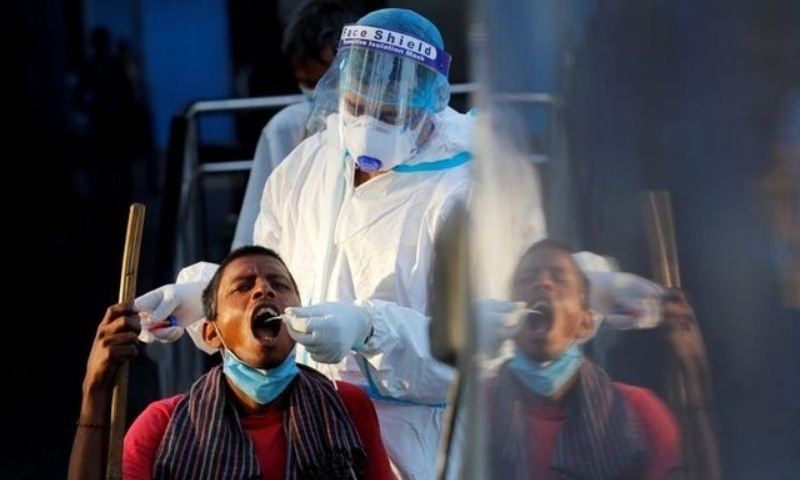 A healthcare worker collects a Covid-19 test swab sample from a man at a temporary shelter for homeless people in New Delhi, India, March 31. &mdash; Reuters