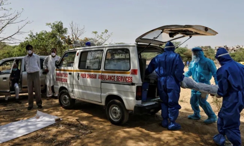 Health workers carry the body of a man who died from Covid-19, for burial at a graveyard in New Delhi, India, April 9. &mdash; Reuters