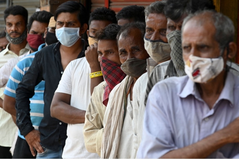 People stand in a queue as they wait for food to be distributed by social workers during weekend lockdown restrictions imposed by the state government amidst rising Covid-19 coronavirus cases, in Mumbai on April 11. — AFP