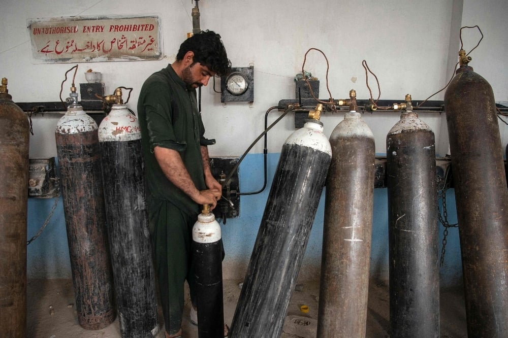 A worker fills oxygen cylinders for hospital use on Covid-19 coronavirus patients, at a factory in Peshawar on April 13. &mdash; AFP