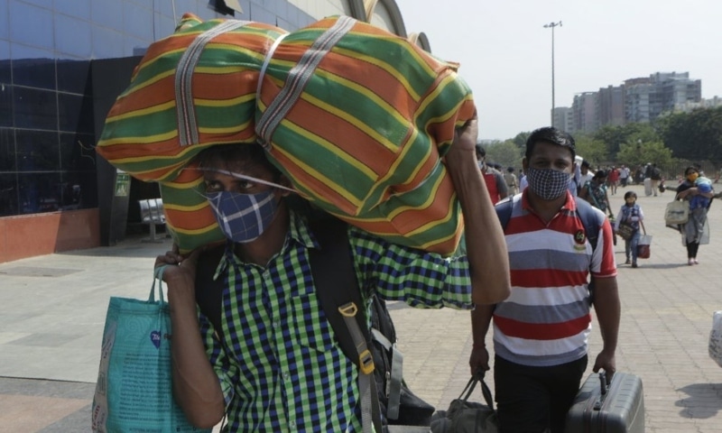 People wearing masks as a precaution against the coronavirus walk to board trains at Lokmanya Tilak Terminus in Mumbai, India, April 16. — AP