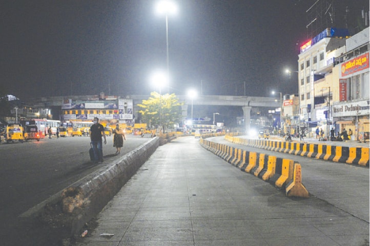 People walk along a deserted road in Hyderabad during a night curfew imposed by the government of Telangana state amidst rising coronavirus cases.—AFP