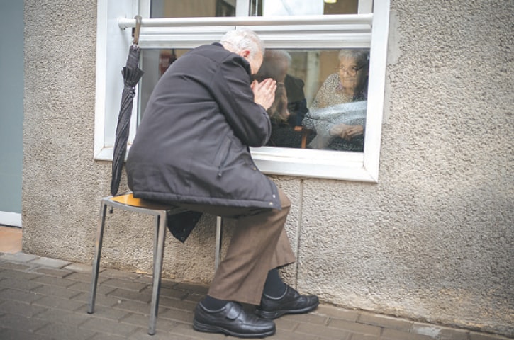 JAVIER Anto prays in front of his wife through a window separating the nursing home from the street in Barcelona.—AP