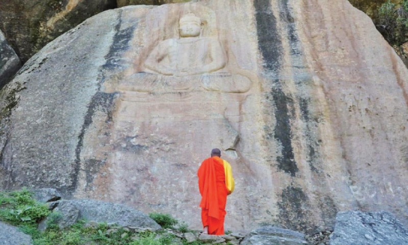 A Buddhist monk praying in front of the meditating Buddha in Jahanabad, Swat. The statue blown up by militants was restored by the department of archaeology and museums. — Dawn