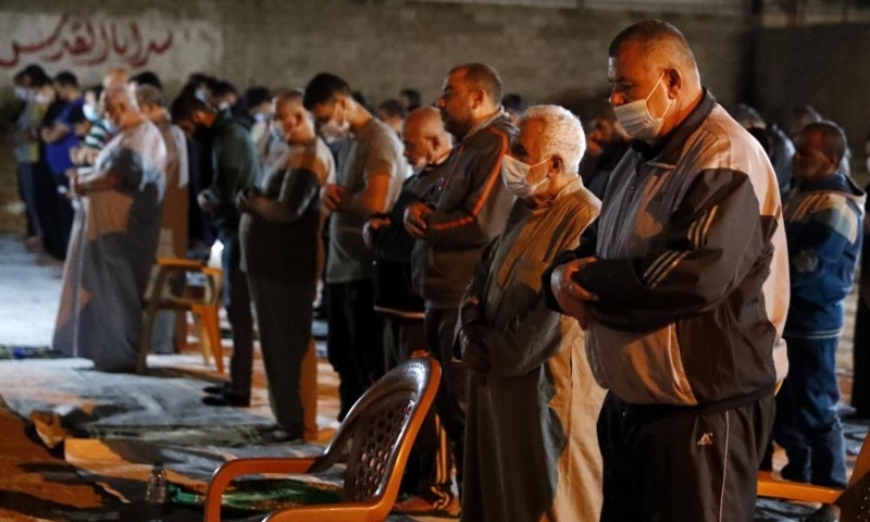 People, some wearing masks to help prevent the spread of the coronavirus, pray the evening prayer during the Muslim holy fasting month of Ramazan, outside a mosque in Gaza City, April 20. — AP