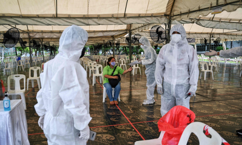Medical workers wearing personal protective equipment talk to a woman waiting to be tested for Covid-19 at the Thai-Japanese Stadium, also known as the Bangkok Youth Centre, in Bangkok. — AFP