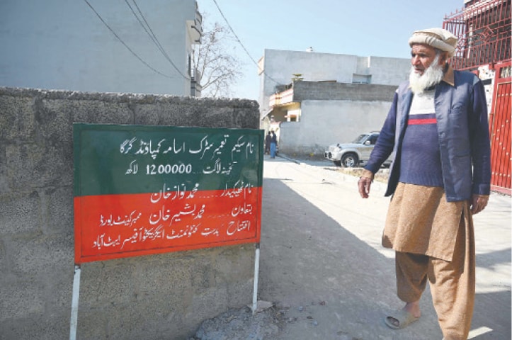 In this picture taken on Feb 11, Altaf Hussain, who was a neighbour of slain Al Qaeda leader Osama bin Laden, stands next to a signboard at the site of the demolished compound where Bin Laden stayed in Abbottabad.—AFP