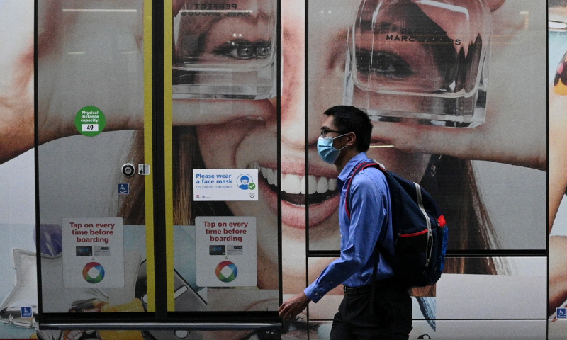 A person wearing a protective face mask walks past a tram with a public health sign asking people to wear masks in Sydney, Australia. — Reuters/File