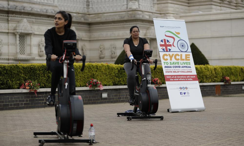 People take part in "Cycle to Save Lives" a 48 hour, non-stop static relay cycle challenge at the BAPS Shri Swaminarayan Mandir in the UK to raise money to help coronavirus relief efforts in India. — AP