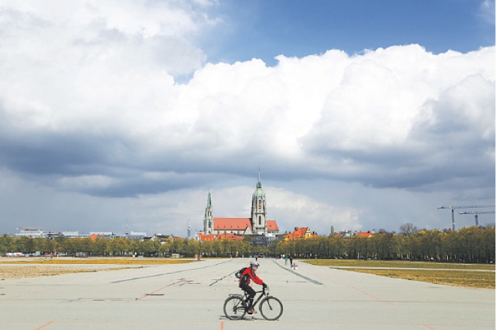 A CYCLIST crosses the Oktoberfest beer festival area in front of St. Paul’s church in Munich.—AP