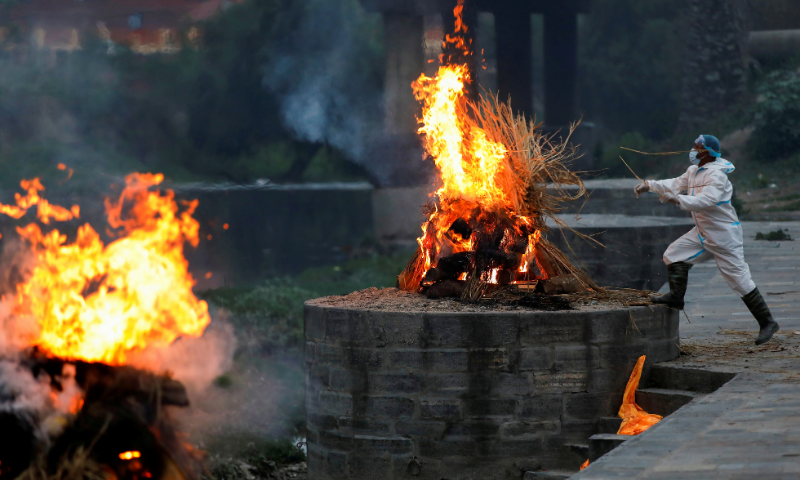 A man wearing personal protective equipment cremates a body of a coronavirus victim at a crematory in Kathmandu, Nepal. — Reuters