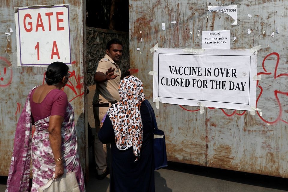 A policeman asks people to leave as they stand outside the gate of a vaccination centre which was closed due to unavailability of Covid-19 vaccine, in Mumbai, India, May 3. &mdash; Reuters