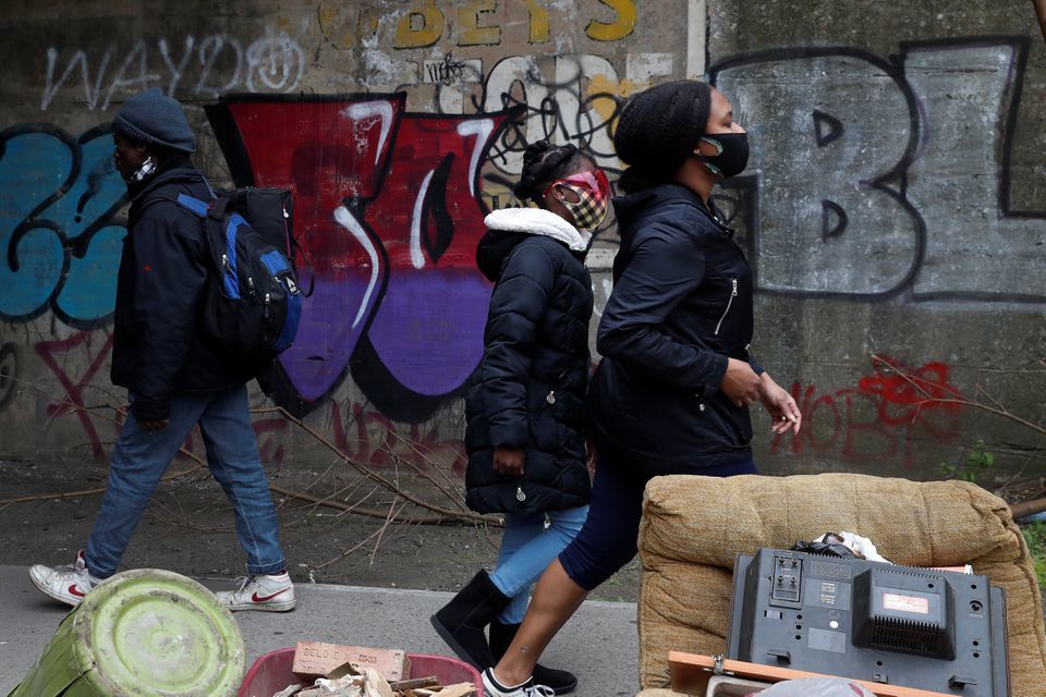 People wearing protective masks walk by a man not wearing a mask over his nose under the subway in the Brownsville section of the Brooklyn borough of New York City, US, May 3. — Reuters