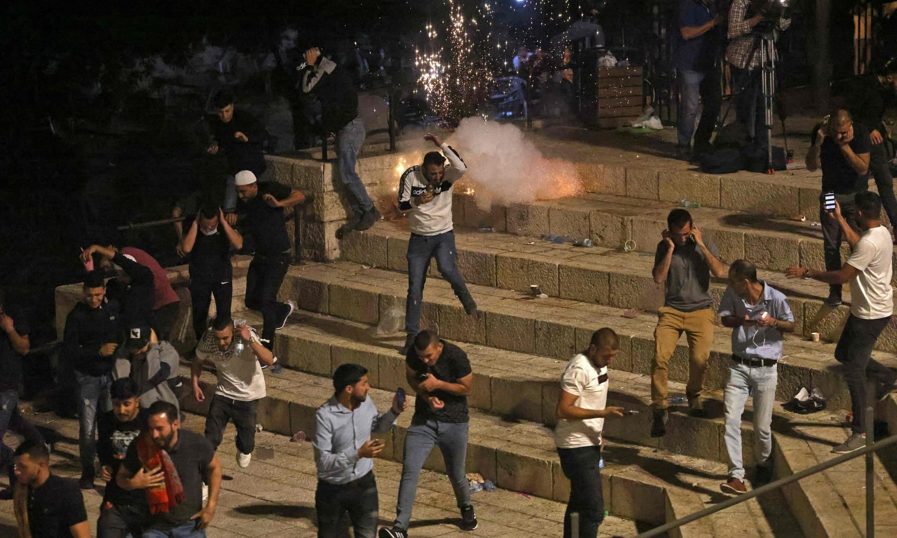 Palestinian protesters run from stun grenades fired by Israeli security forces outside the Damascus Gate in Jerusalem's Old City on May 8, 2021. — AFP