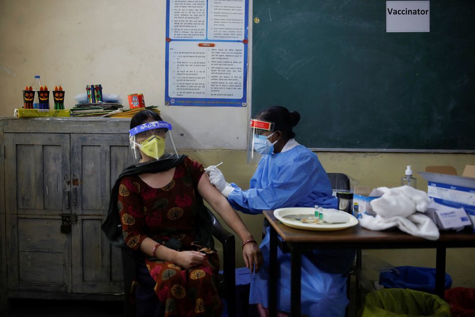 A healthcare worker gives a dose of Covishield, a coronavirus disease vaccine manufactured by Serum Institute of India, to a woman inside a classroom of a school, which has been converted into a temporary vaccination centre, in New Delhi, India, May 4. — Reuters
