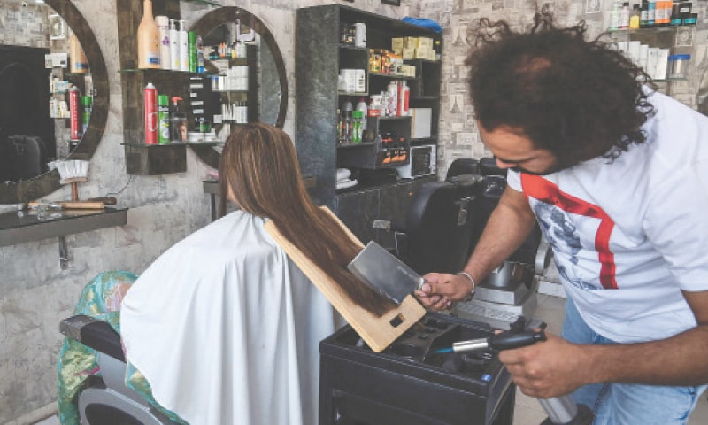 BARBER Ali Abbas uses a butcher&rsquo;s knife to cut the hair of a customer at his shop in Lahore.&mdash;AFP