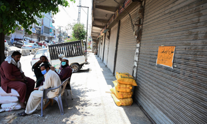 In this file photo, shopkeepers sit along a closed market after a shutdown was imposed in a bid to prevent a surge in Covid-19 cases during Eid in Rawalpindi. — AFP/File