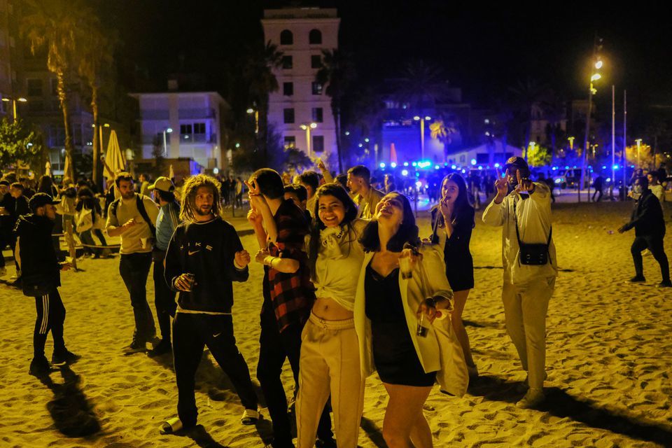 People gather in front of police officers patrolling Barceloneta beach, Barcelona, Spain, May 15. — Reuters