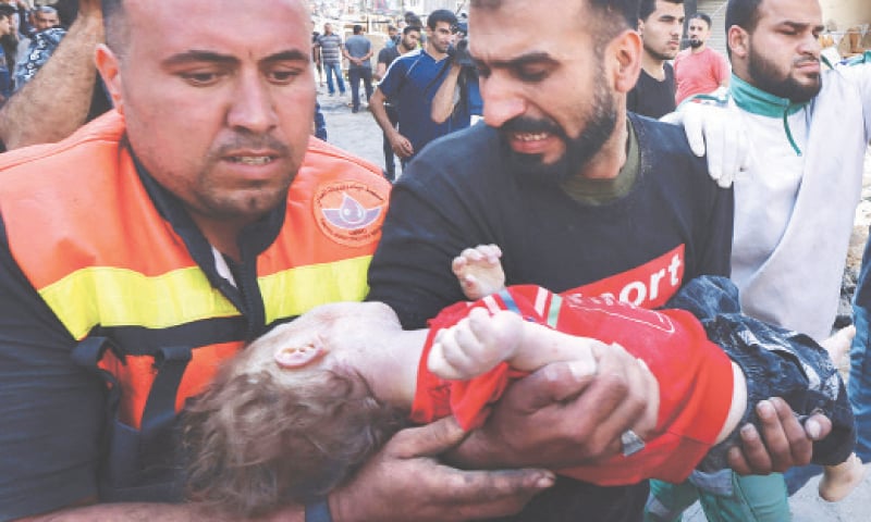 Palestinians recover the body of a child from the rubble of the destroyed building in Rimal. — AFP