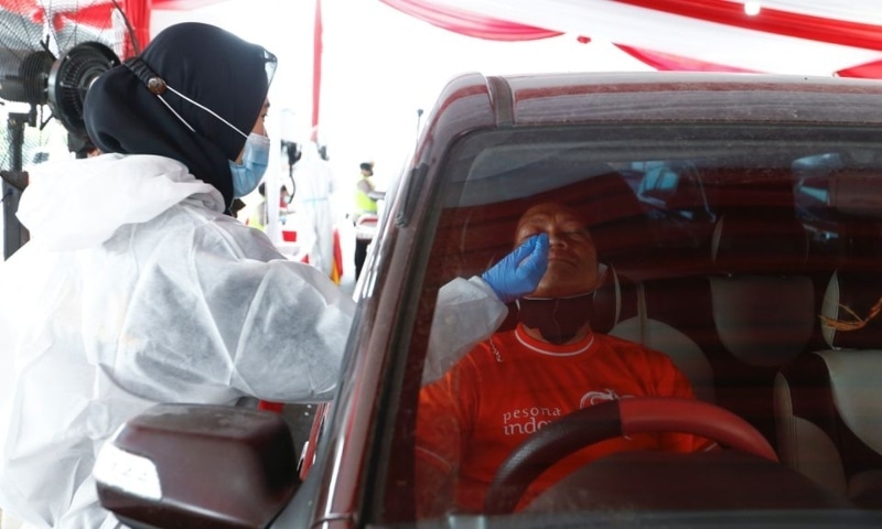A healthcare worker takes a swab sample from a person to be tested for Covid-19 as travellers return to the capital city after the Eidul Fitr festival, Cikarang, Bekasi, on the outskirts of Jakarta, Indonesia, May 17. — Reuters
