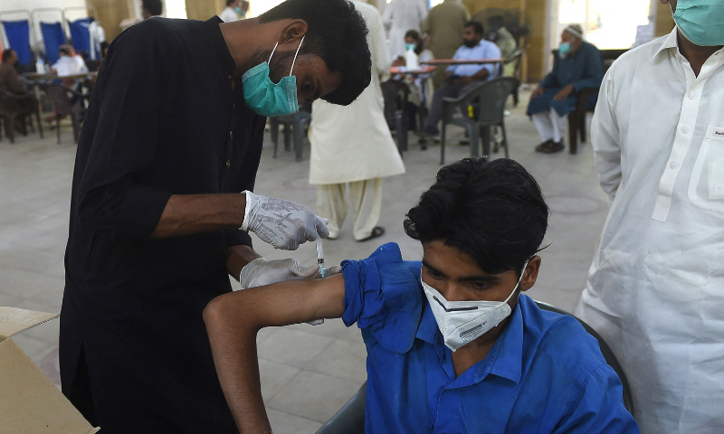 A health worker inoculates a man with a dose of AstraZeneca-Oxford's coronavirus vaccine at a vaccination centre in Karachi on Tuesday. — AFP