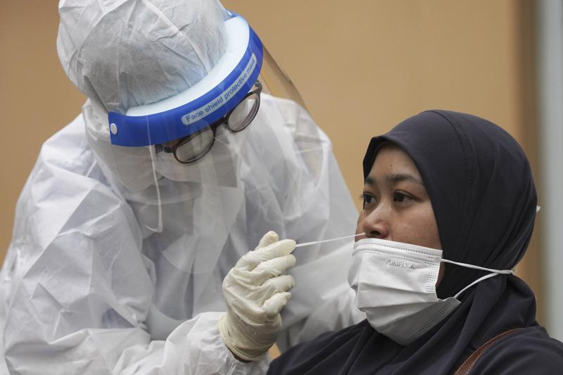 A medical worker collects a swab sample from a woman during coronavirus testing at a Covid-19 testing centre in Ulu Klang, on the outskirts of Kuala Lumpur, Malaysia, May 18. &mdash; AP