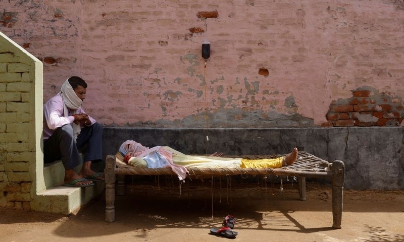 A man sits next to his wife, who is suffering from fever as she receives treatment at a clinic set up by a local villager, in Parsaul village in Greater Noida, in the northern state of Uttar Pradesh, India, May 22. — Reuters A man sits next to his wife, who is suffering from fever as she receives treatment at a clinic set up by a local villager, in Parsaul village in Greater Noida, in the northern state of Uttar Pradesh, India, May 22. — Reuters