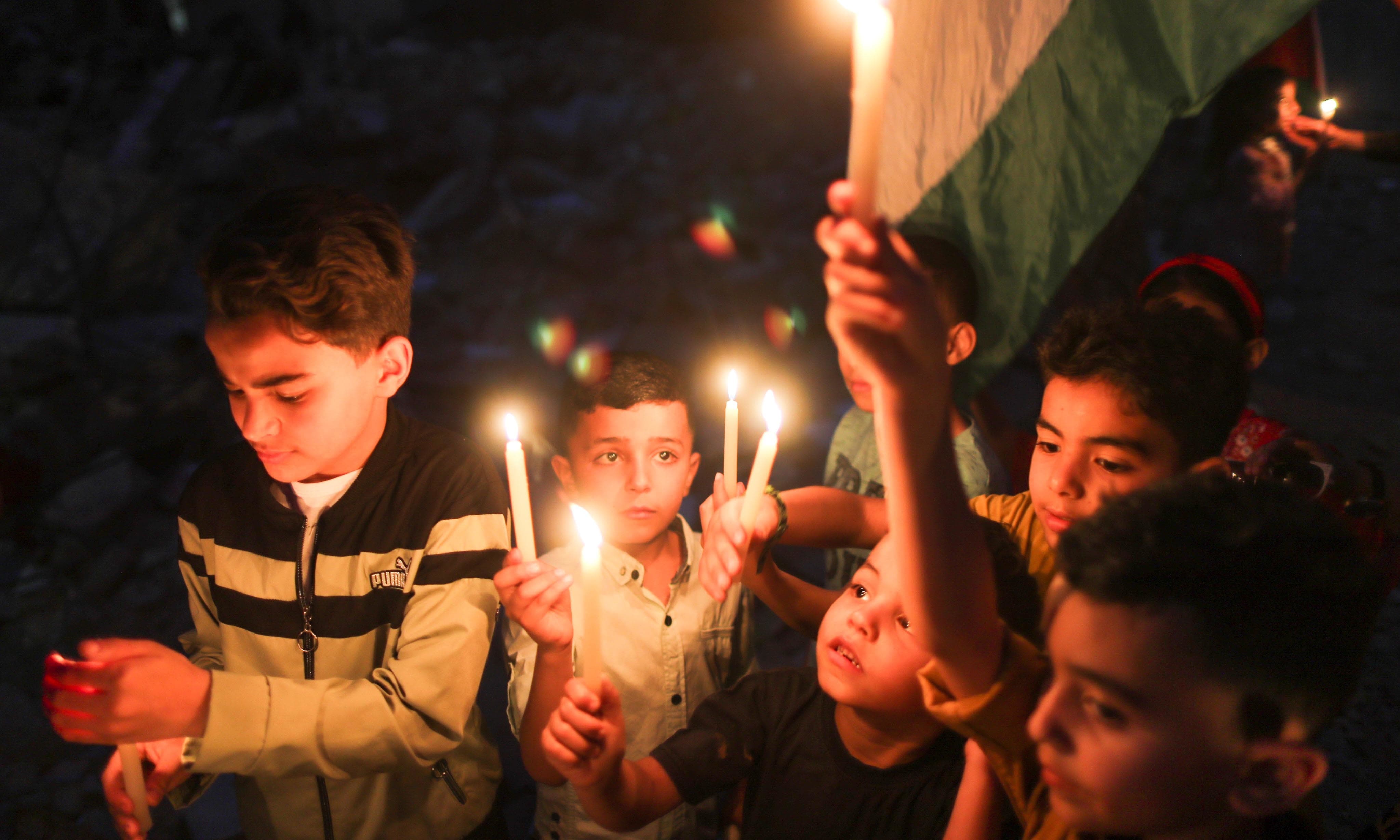 Children hold candles at the site of a house that was destroyed by Israeli air strikes, in Gaza May 23. — Reuters