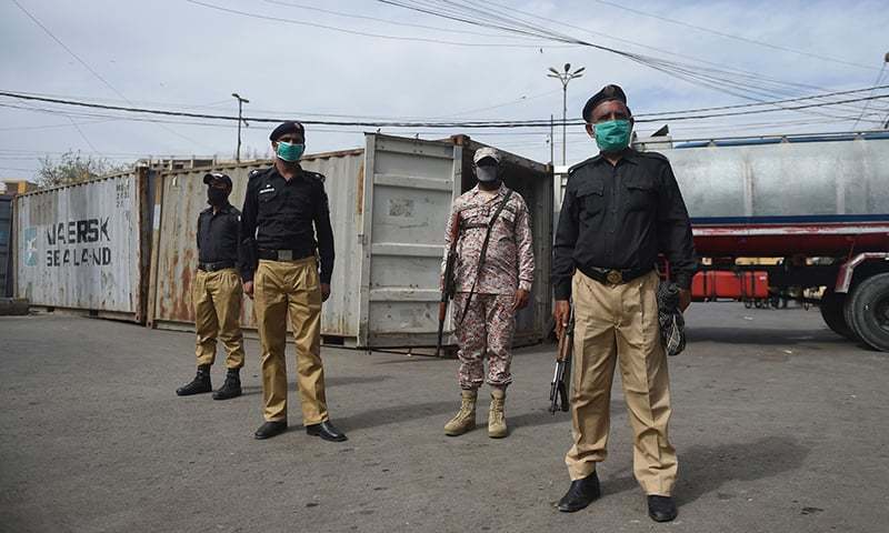 Security personnel wearing facemasks stand guard beside containers which authorities sealed after some people tested positive for coronavirus, during a government-imposed nationwide lockdown as a preventive measure against the Covid-19 coronavirus, in Karachi. — AFP/ File