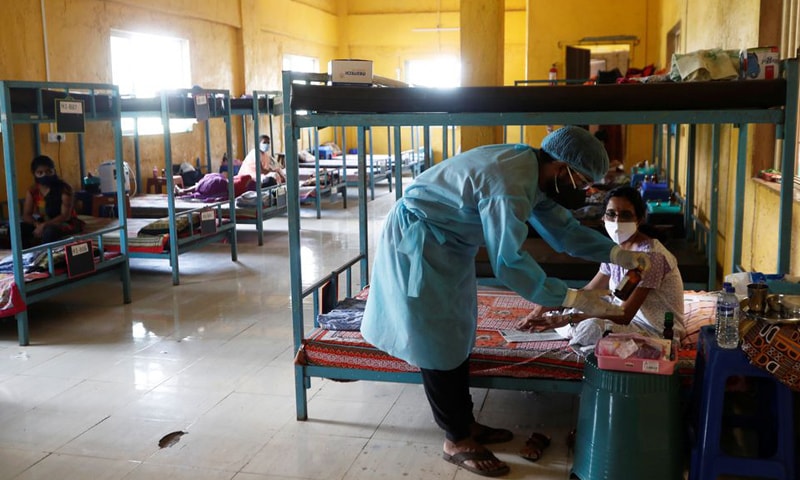 A doctor checks the medicines of a patient suffering from Covid-19 inside a classroom turned coronavirus care facility on the outskirts of Mumbai, India. — Reuters