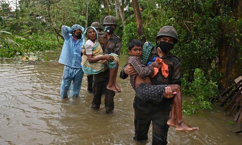 Indian army personnel wade across a flooded village road, carrying people to safety, as Cyclone Yaas barrels towards India's eastern coast in the Bay of Bengal. — AFP Indian army personnel wade across a flooded village road, carrying people to safety, as Cyclone Yaas barrels towards India's eastern coast in the Bay of Bengal. — AFP