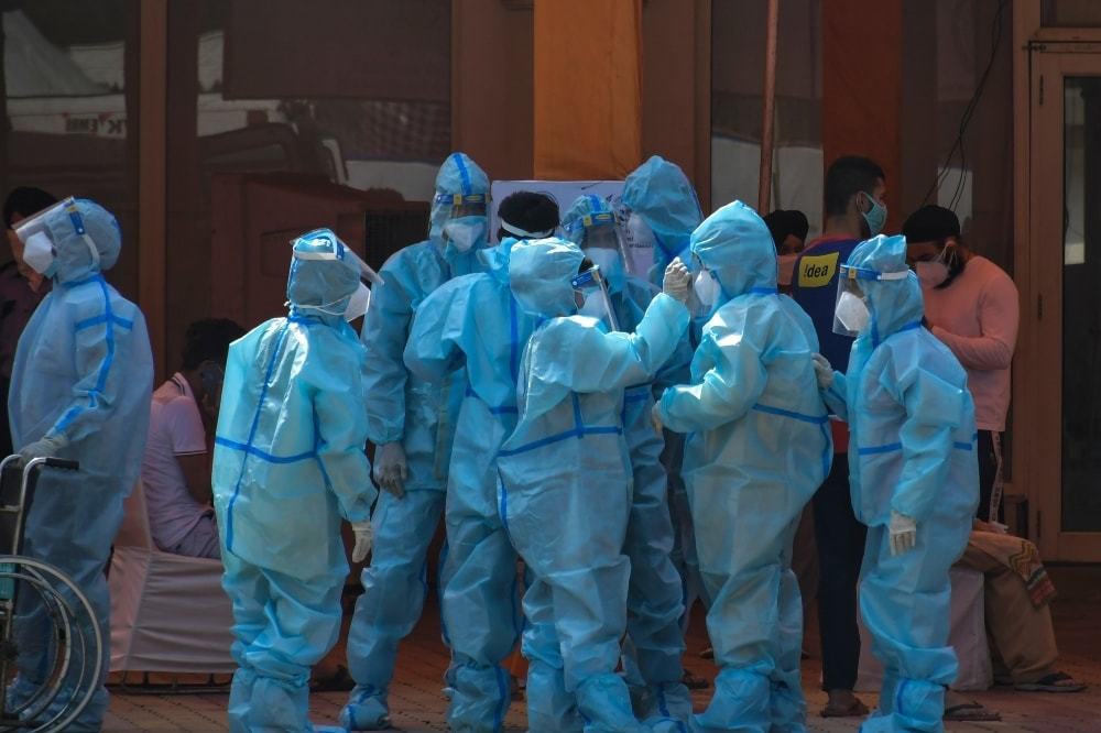 Health workers and volunteers in personal protective suits wait to receive patients outside a Covid-19 hospital in New Delhi. — AP/File